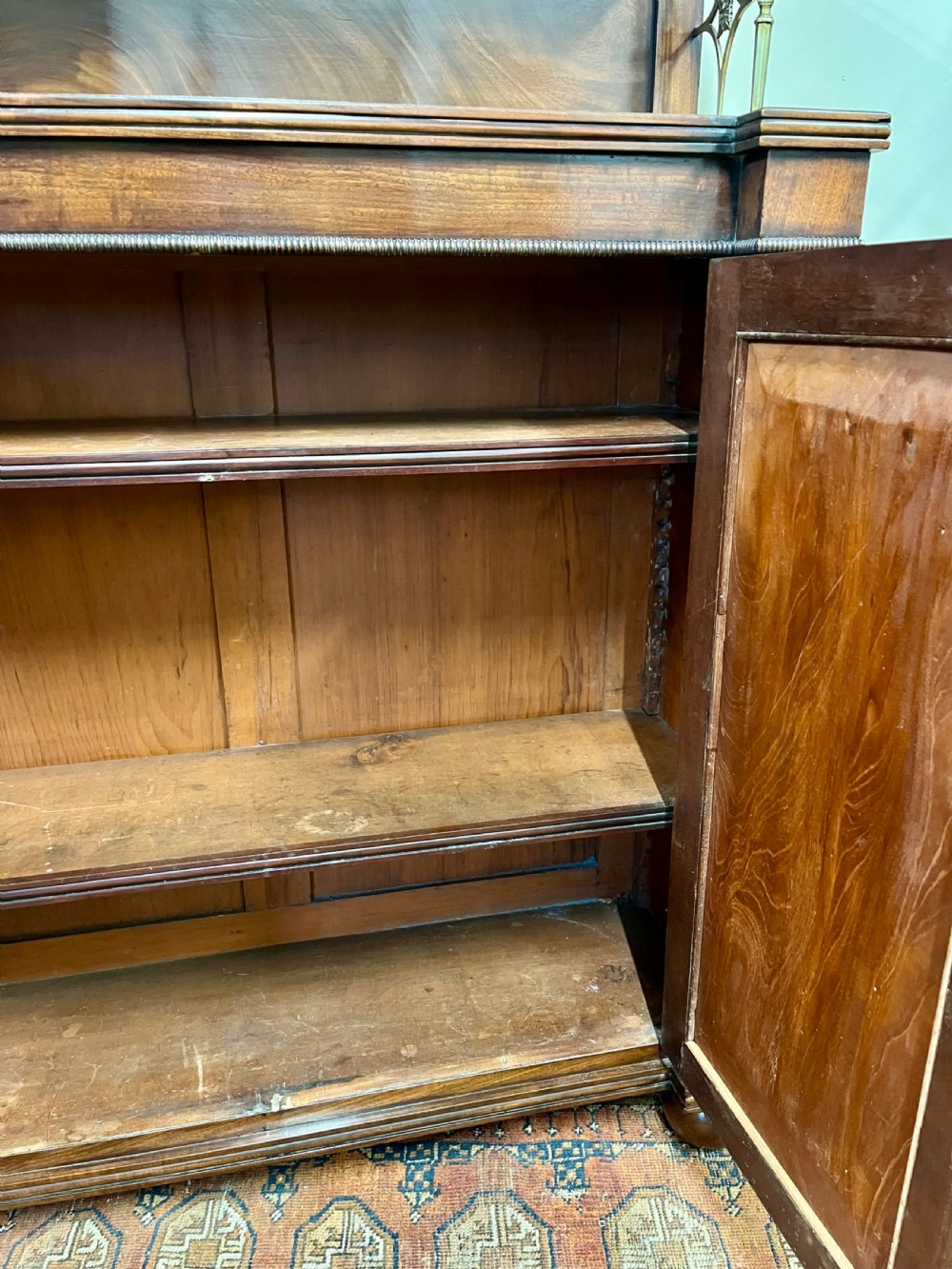 A 19th-century mahogany chiffonier featuring an upper shelf with a brass gallery, twin panelled cupboard doors flanked by turned side columns, resting on bun feet. View IX