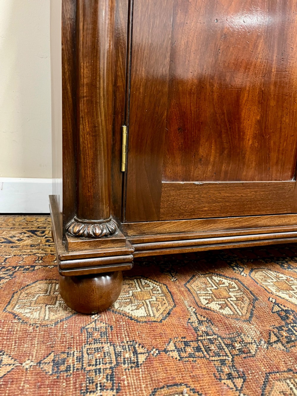 A 19th-century mahogany chiffonier featuring an upper shelf with a brass gallery, twin panelled cupboard doors flanked by turned side columns, resting on bun feet. View X
