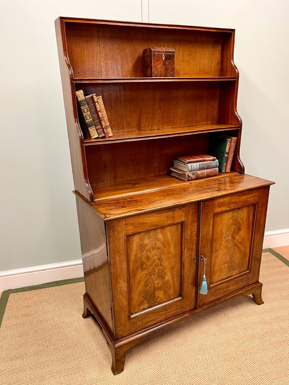 A 19th-century mahogany waterfall bookcase with three graduated open shelves over a two-door cabinet resting on bracket feet.