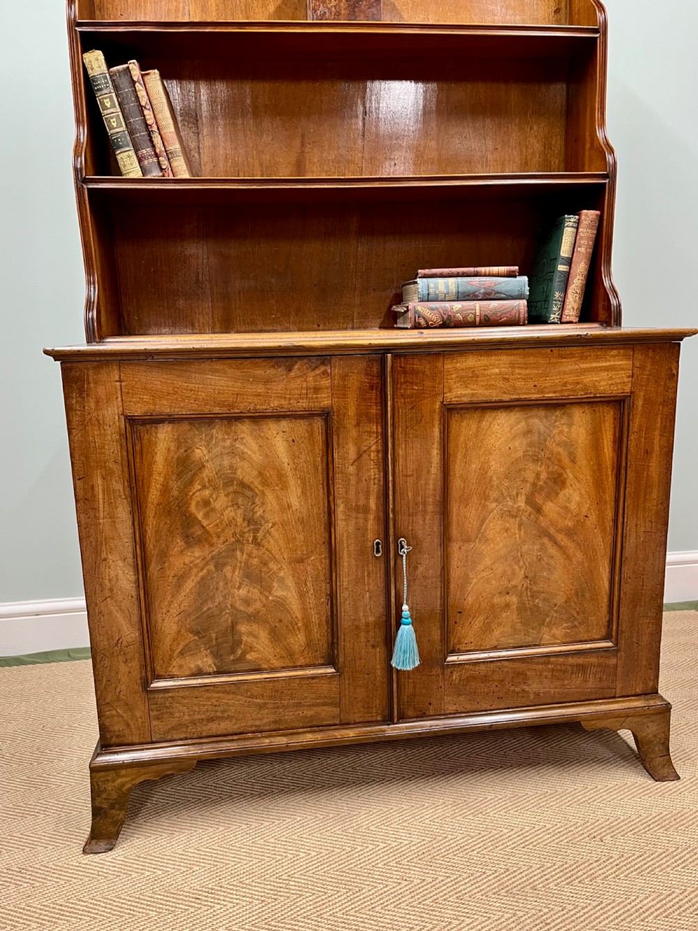 A 19th-century mahogany waterfall bookcase with three graduated open shelves over a two-door cabinet resting on bracket feet. View II