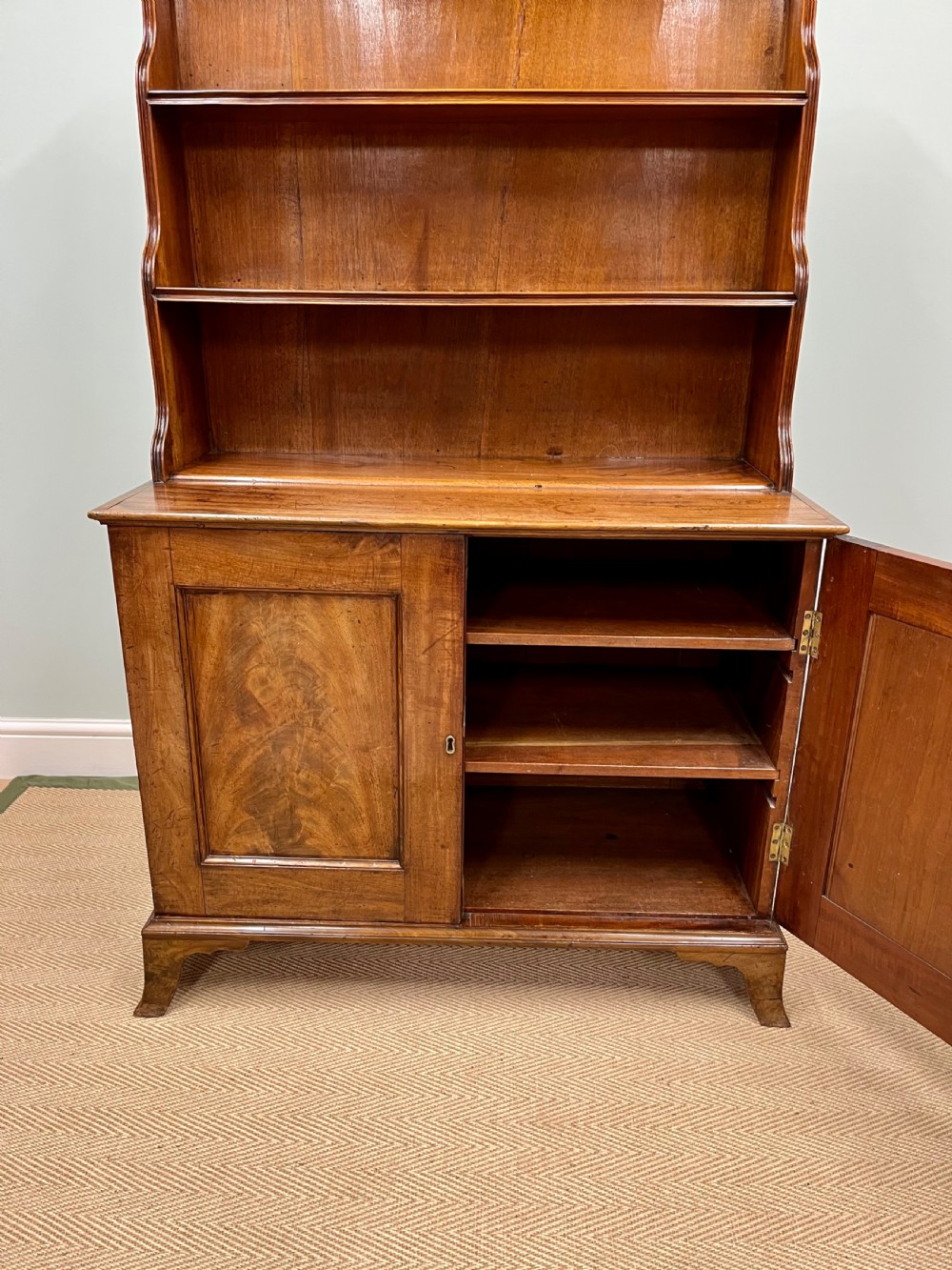 A 19th-century mahogany waterfall bookcase with three graduated open shelves over a two-door cabinet resting on bracket feet. View IV