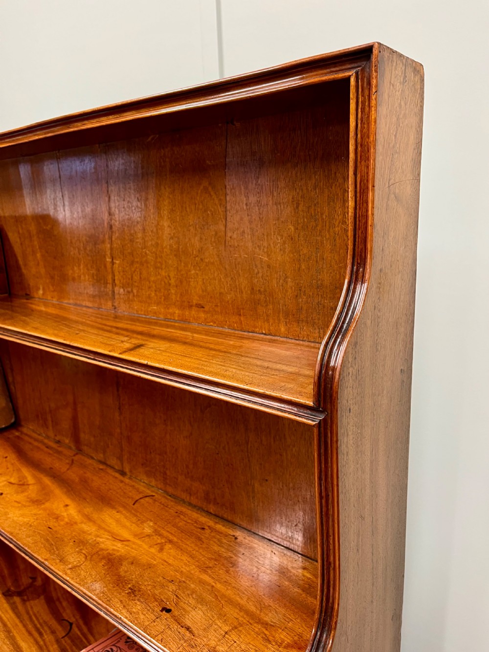 A 19th-century mahogany waterfall bookcase with three graduated open shelves over a two-door cabinet resting on bracket feet. View VIII