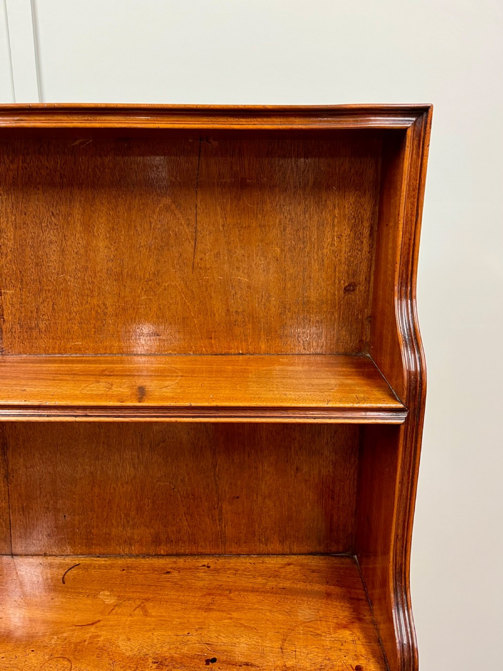 A 19th-century mahogany waterfall bookcase with three graduated open shelves over a two-door cabinet resting on bracket feet. View IX