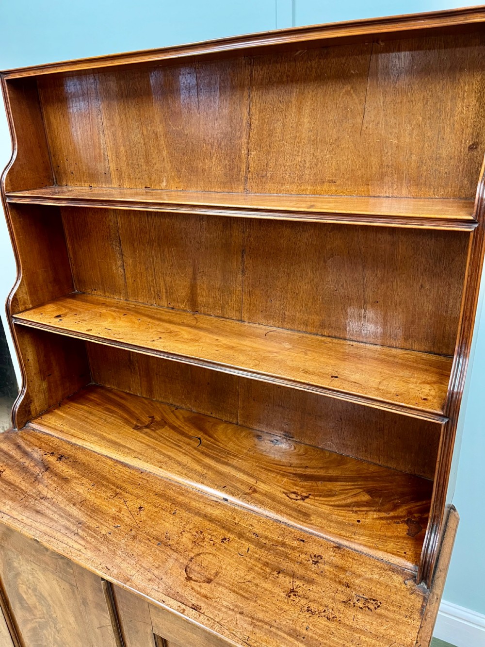 A 19th-century mahogany waterfall bookcase with three graduated open shelves over a two-door cabinet resting on bracket feet. View X
