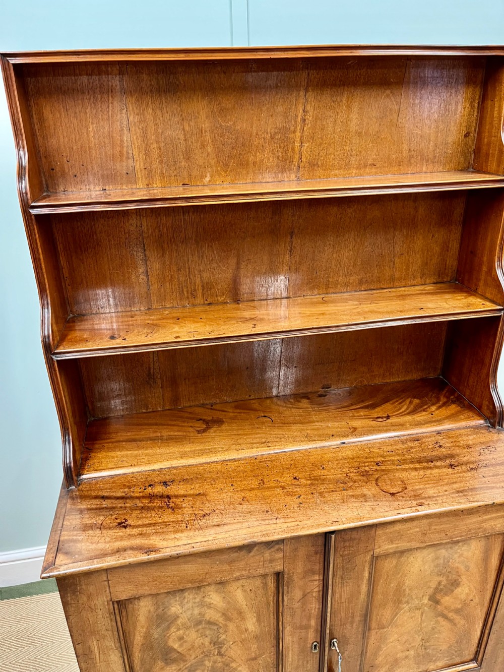 A 19th-century mahogany waterfall bookcase with three graduated open shelves over a two-door cabinet resting on bracket feet. View XI