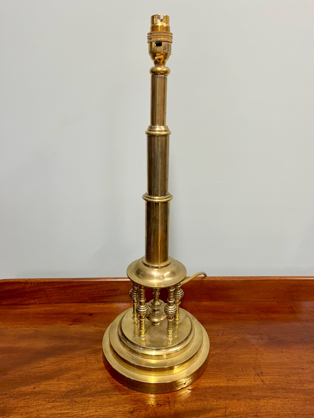 An antique turned brass Secessionist table lamp base featuring a stepped circular pedestal and miniature decorative columns around the lower stem.