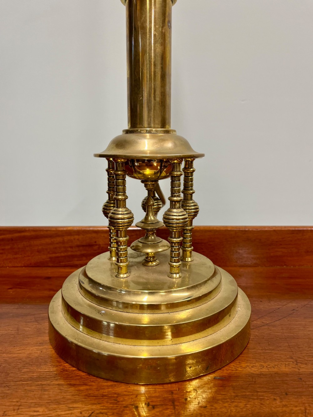 An antique turned brass Secessionist table lamp base featuring a stepped circular pedestal and miniature decorative columns around the lower stem. View II