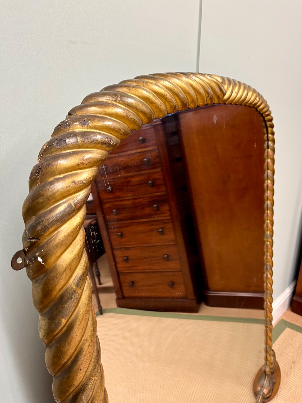A 19th-century arched overmantel mirror with a gold gilded rope-twist frame and scrolled corner supports. View II