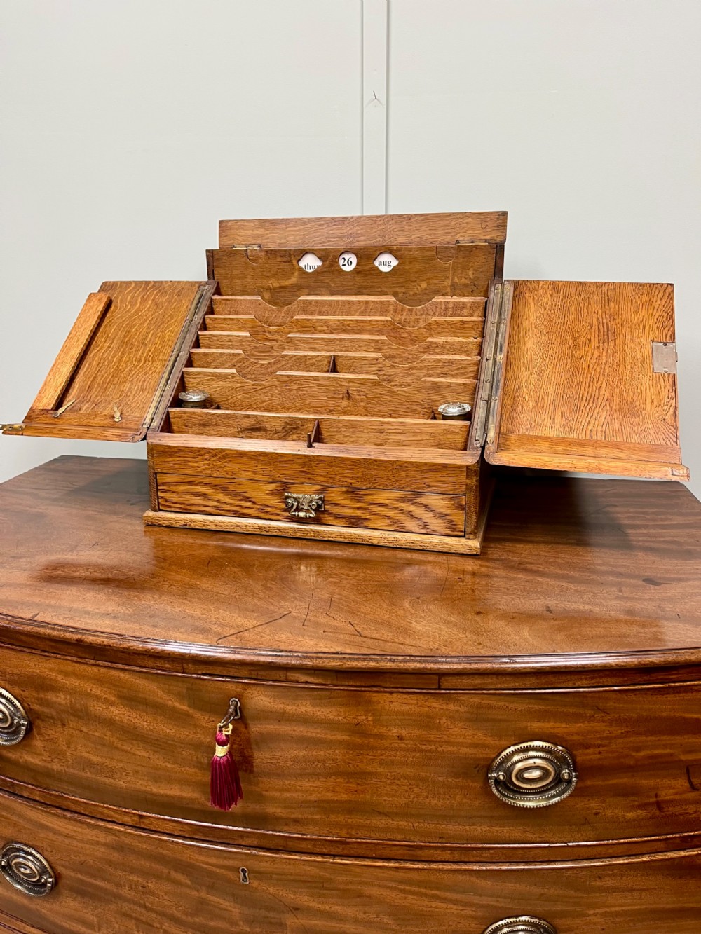 A Victorian oak stationery cabinet with open doors showing stepped letter compartments, a built-in calendar mechanism, inkwell slots, and a lower drawer.