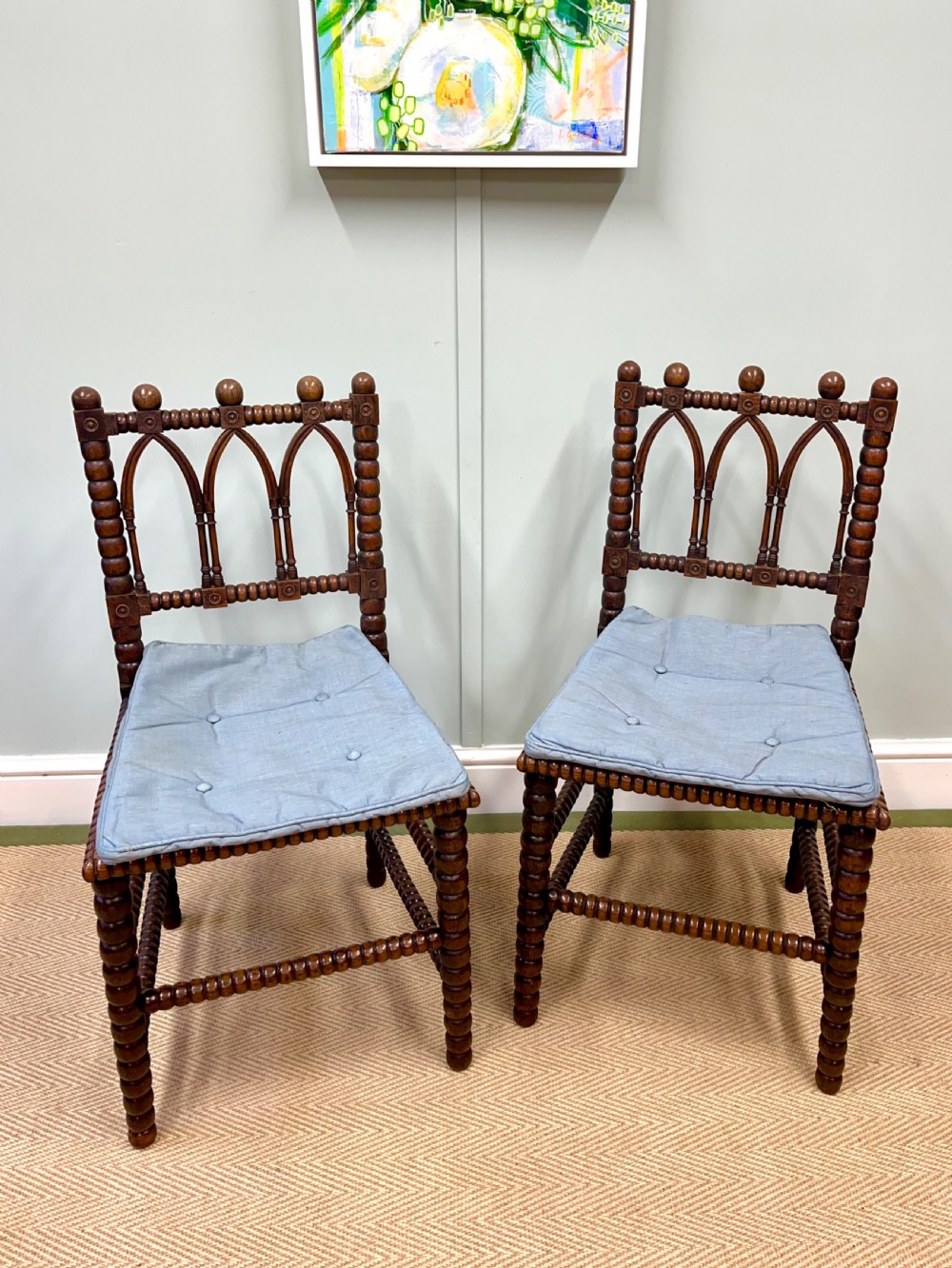 A pair of antique wooden chairs featuring intricate bobbin-turned framing and woven cane seats. View II