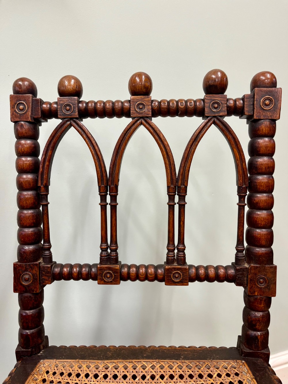 A pair of antique wooden chairs featuring intricate bobbin-turned framing and woven cane seats. View III