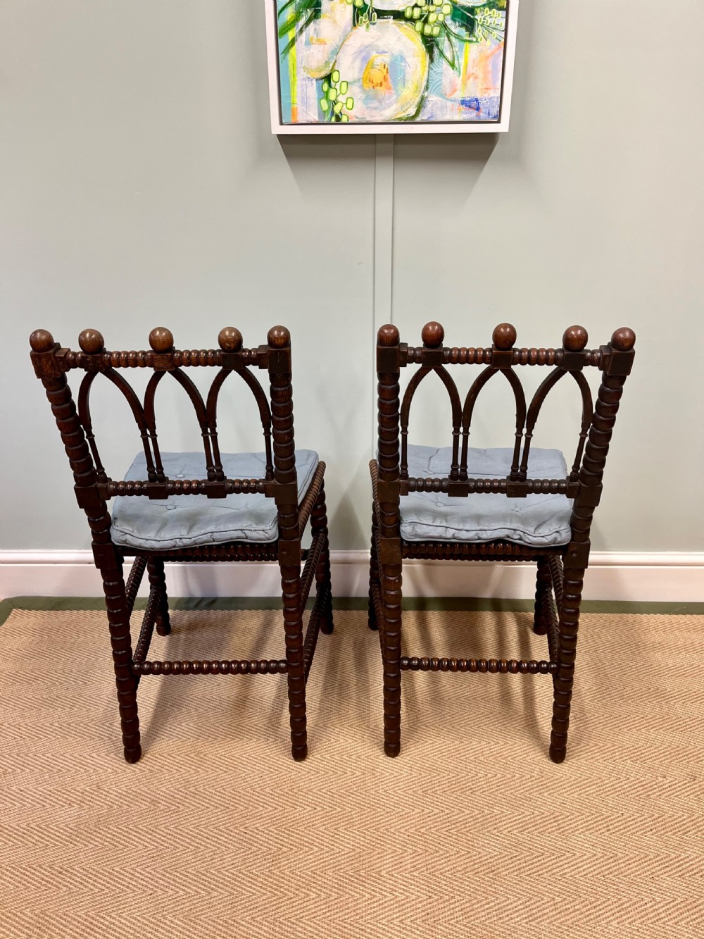 A pair of antique wooden chairs featuring intricate bobbin-turned framing and woven cane seats. View IV