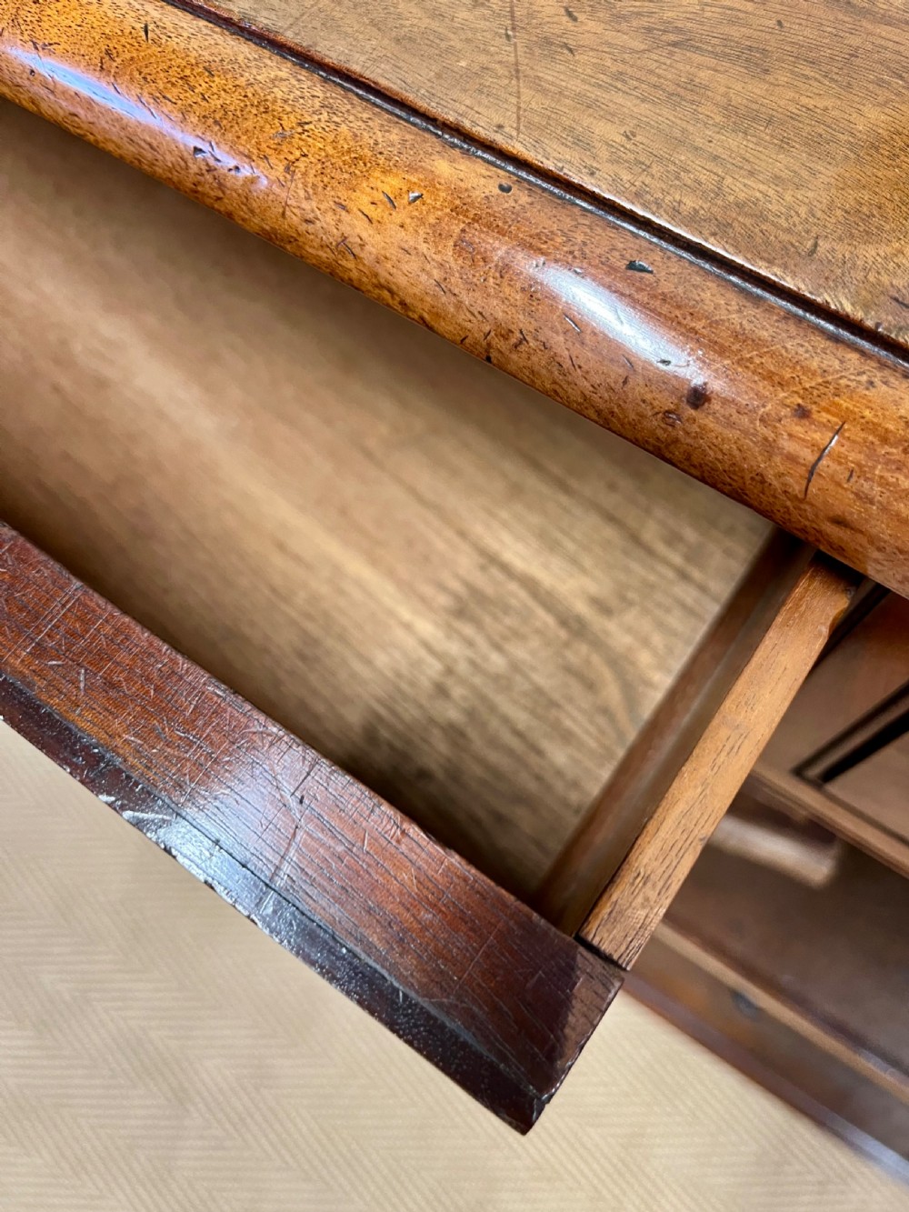 A low 19th-century mahogany bookcase featuring three small drawers above open shelving and supported by turned feet. View VII