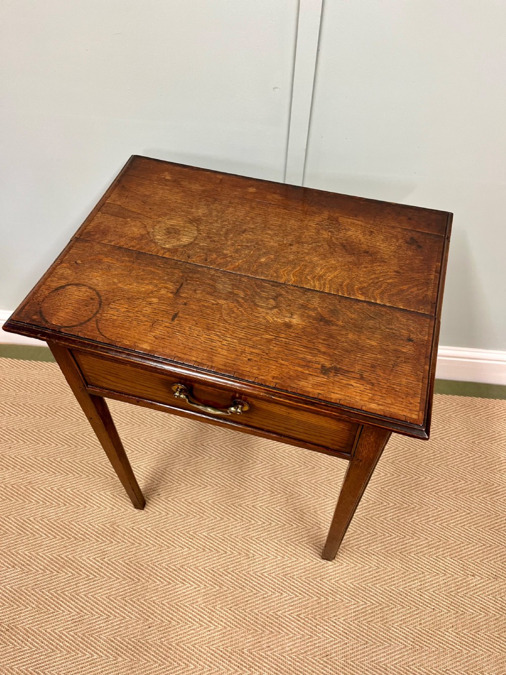 An 18th-century warm brown oak side table featuring a single drawer with a central brass handle and straight square legs. View II