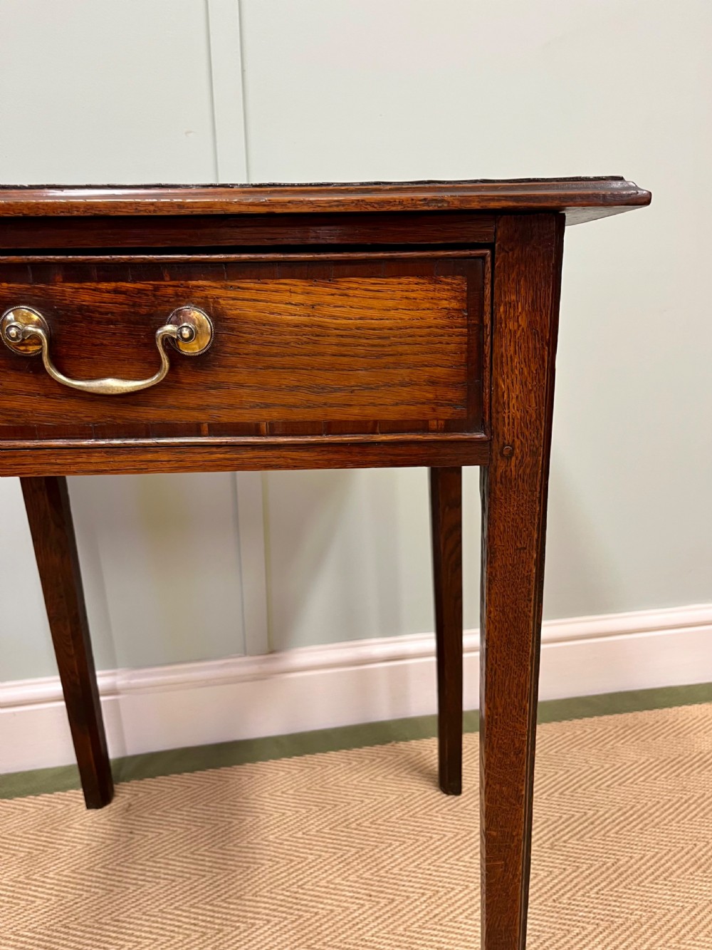 An 18th-century warm brown oak side table featuring a single drawer with a central brass handle and straight square legs. View III