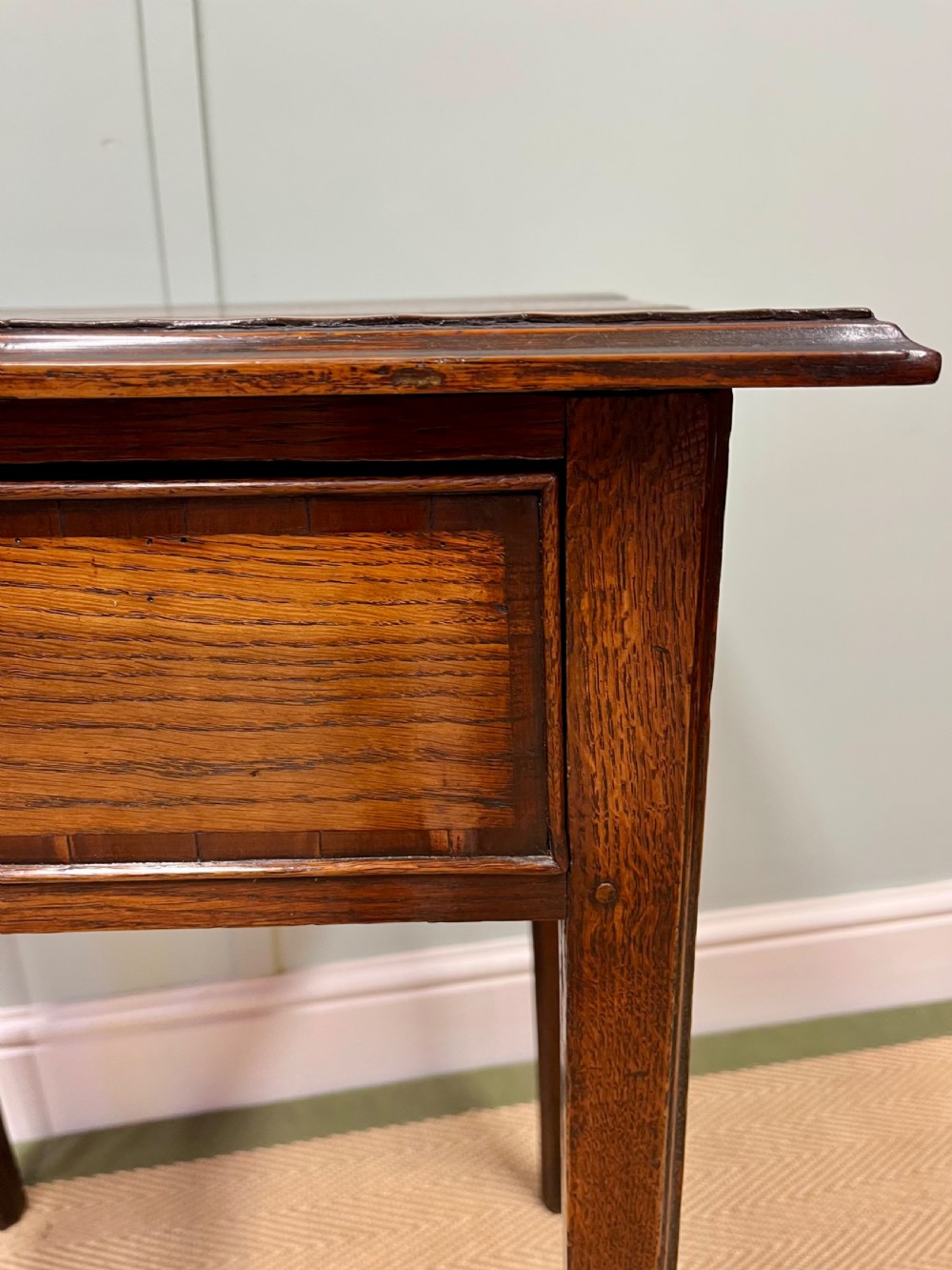 An 18th-century warm brown oak side table featuring a single drawer with a central brass handle and straight square legs. View VI