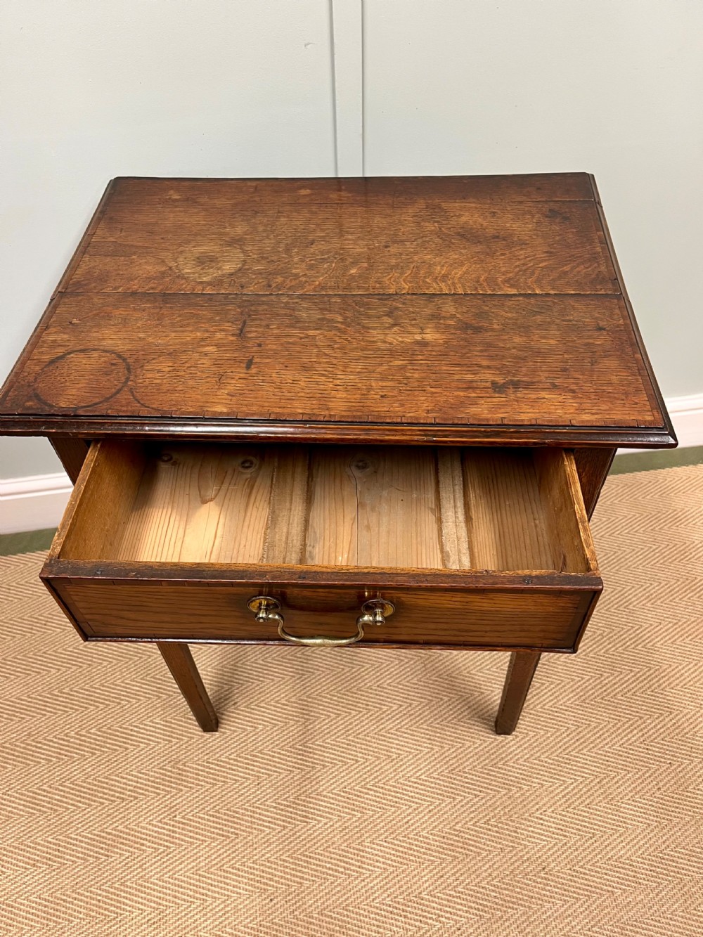 An 18th-century warm brown oak side table featuring a single drawer with a central brass handle and straight square legs. View VII