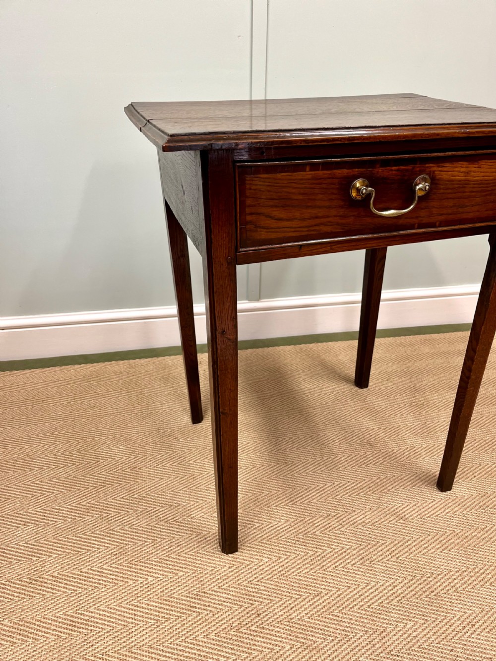 An 18th-century warm brown oak side table featuring a single drawer with a central brass handle and straight square legs. View IX