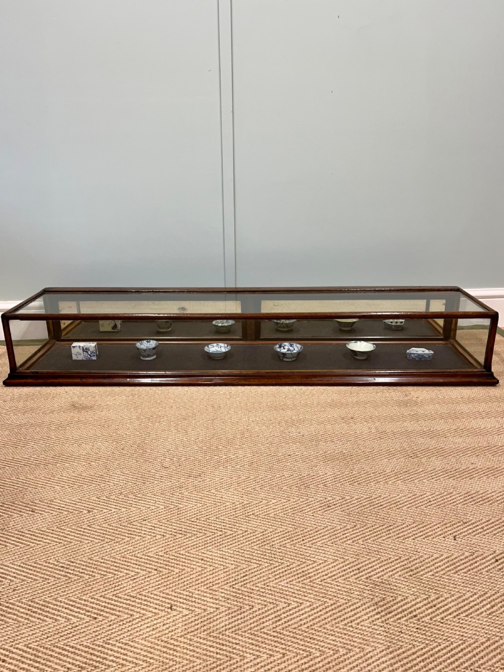 A long, low Victorian mahogany and glass tabletop display case with a moulded base and glazed panels.