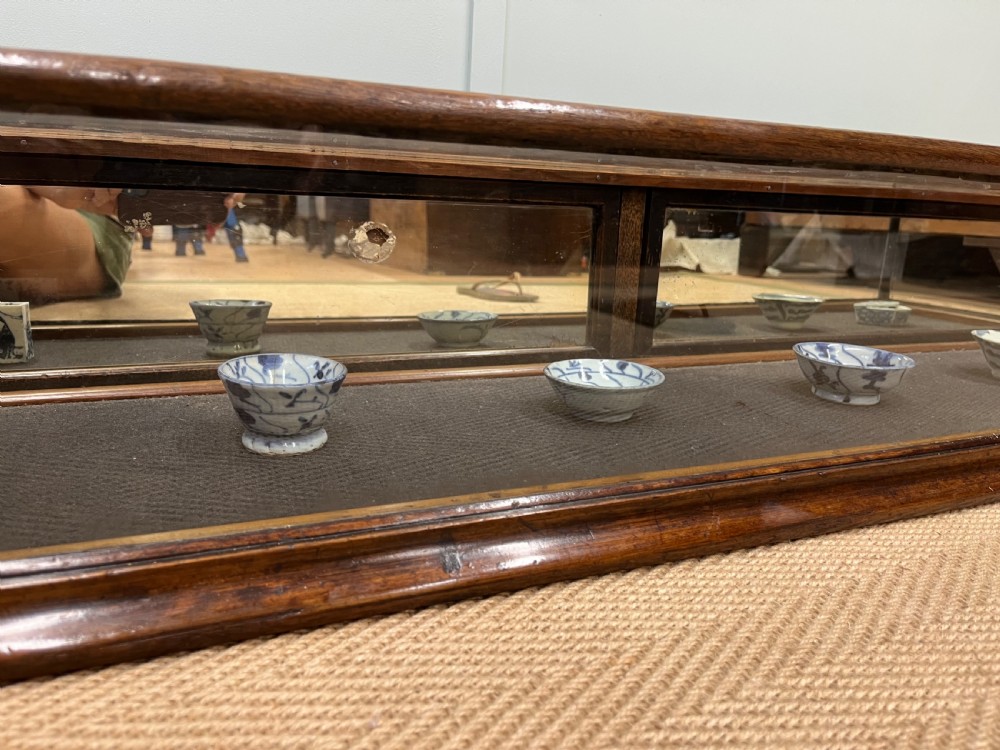 A long, low Victorian mahogany and glass tabletop display case with a moulded base and glazed panels. View VI