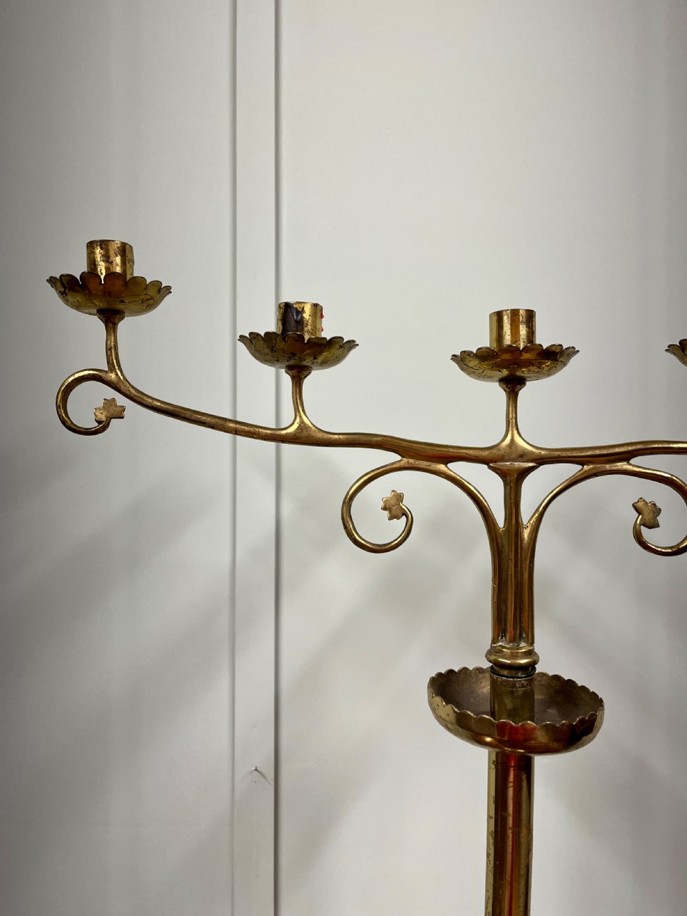 A pair of Gothic Revival brass candelabra featuring tall turned stems and sweeping multi-branch arms with scalloped drip pans. View V