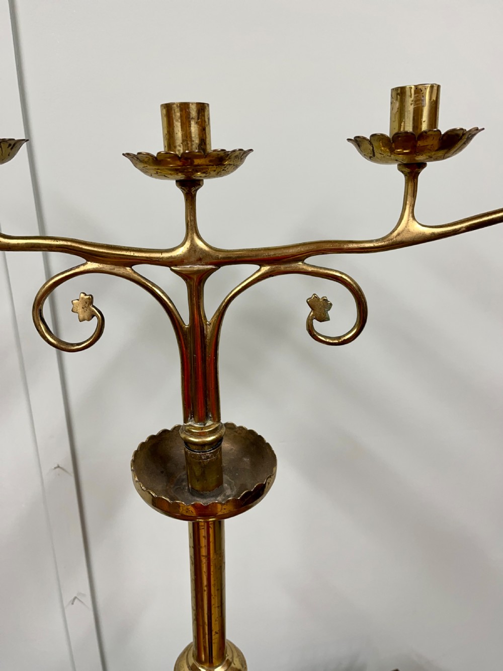 A pair of Gothic Revival brass candelabra featuring tall turned stems and sweeping multi-branch arms with scalloped drip pans. View VI