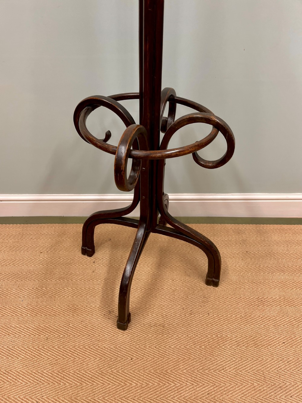 A dark brown Victorian bentwood coat and hat stand featuring curved upper hooks, a central turned column, an integrated umbrella ring, and quadrupled splayed feet. View III