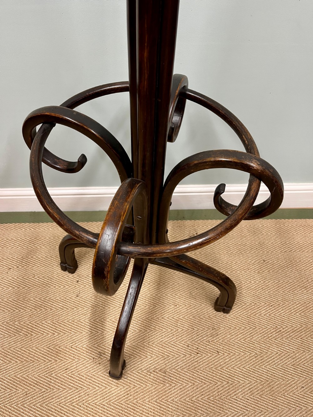 A dark brown Victorian bentwood coat and hat stand featuring curved upper hooks, a central turned column, an integrated umbrella ring, and quadrupled splayed feet. View V