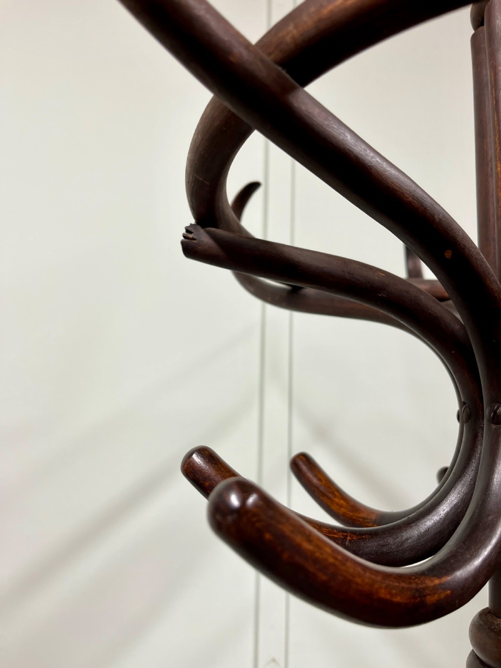 A dark brown Victorian bentwood coat and hat stand featuring curved upper hooks, a central turned column, an integrated umbrella ring, and quadrupled splayed feet. View VII