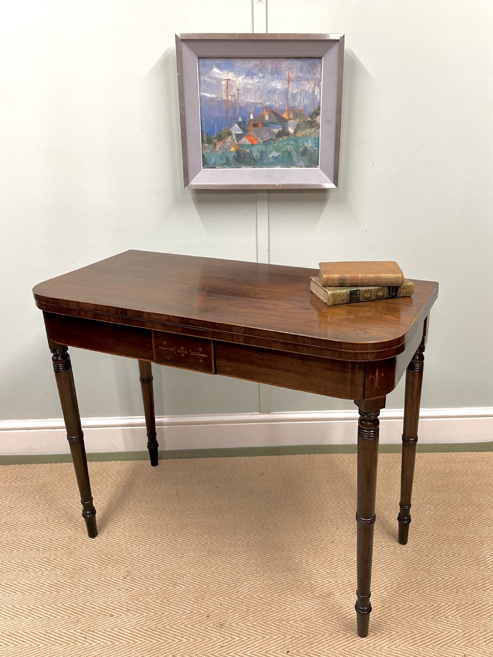 A Regency rosewood fold-over card table with turned legs and subtle inlaid detailing on the apron.