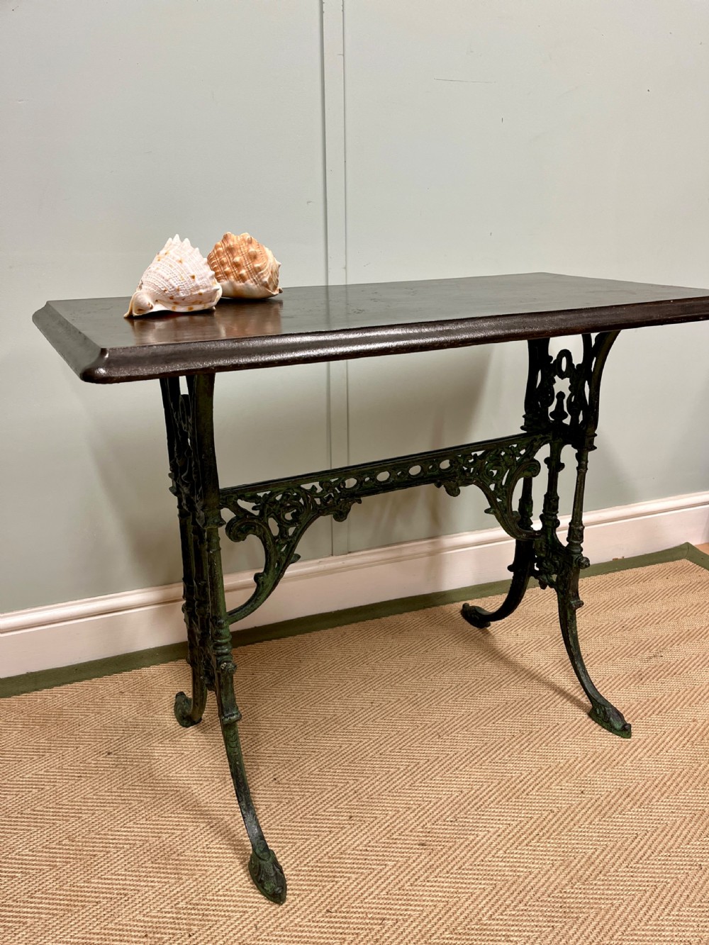 A 19th-century rectangular side table featuring a dark polished timber top supported by a dark green painted cast iron base with scrollwork decoration.