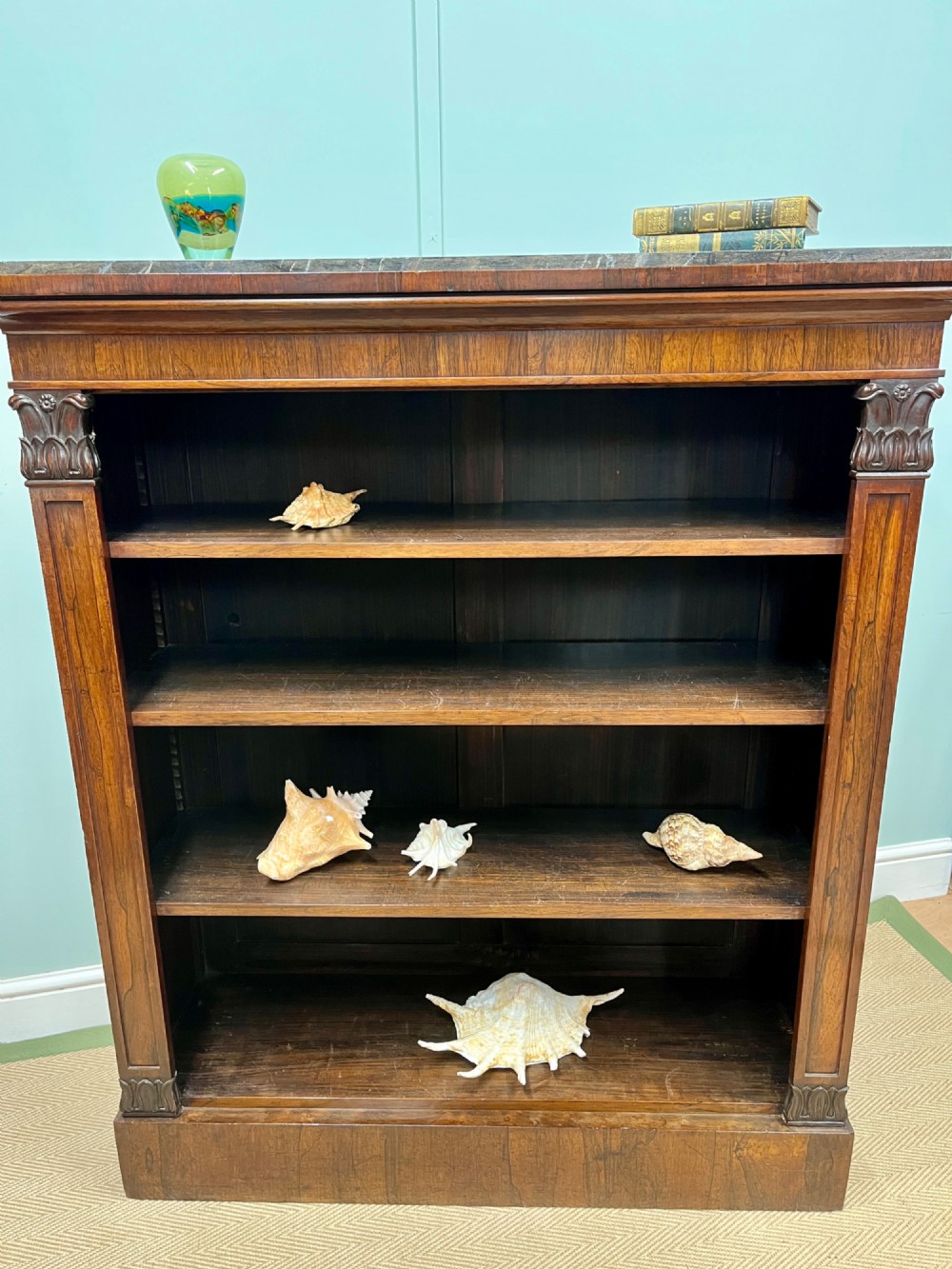 A George IV open rosewood dwarf bookcase featuring carved acanthus pilasters, four open shelves, and a grey marble top. View III