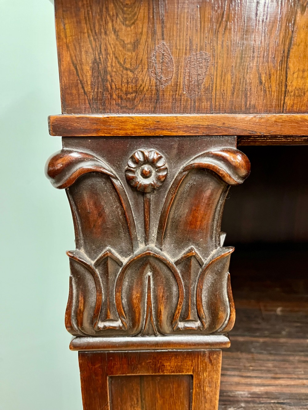 A George IV open rosewood dwarf bookcase featuring carved acanthus pilasters, four open shelves, and a grey marble top. View IX