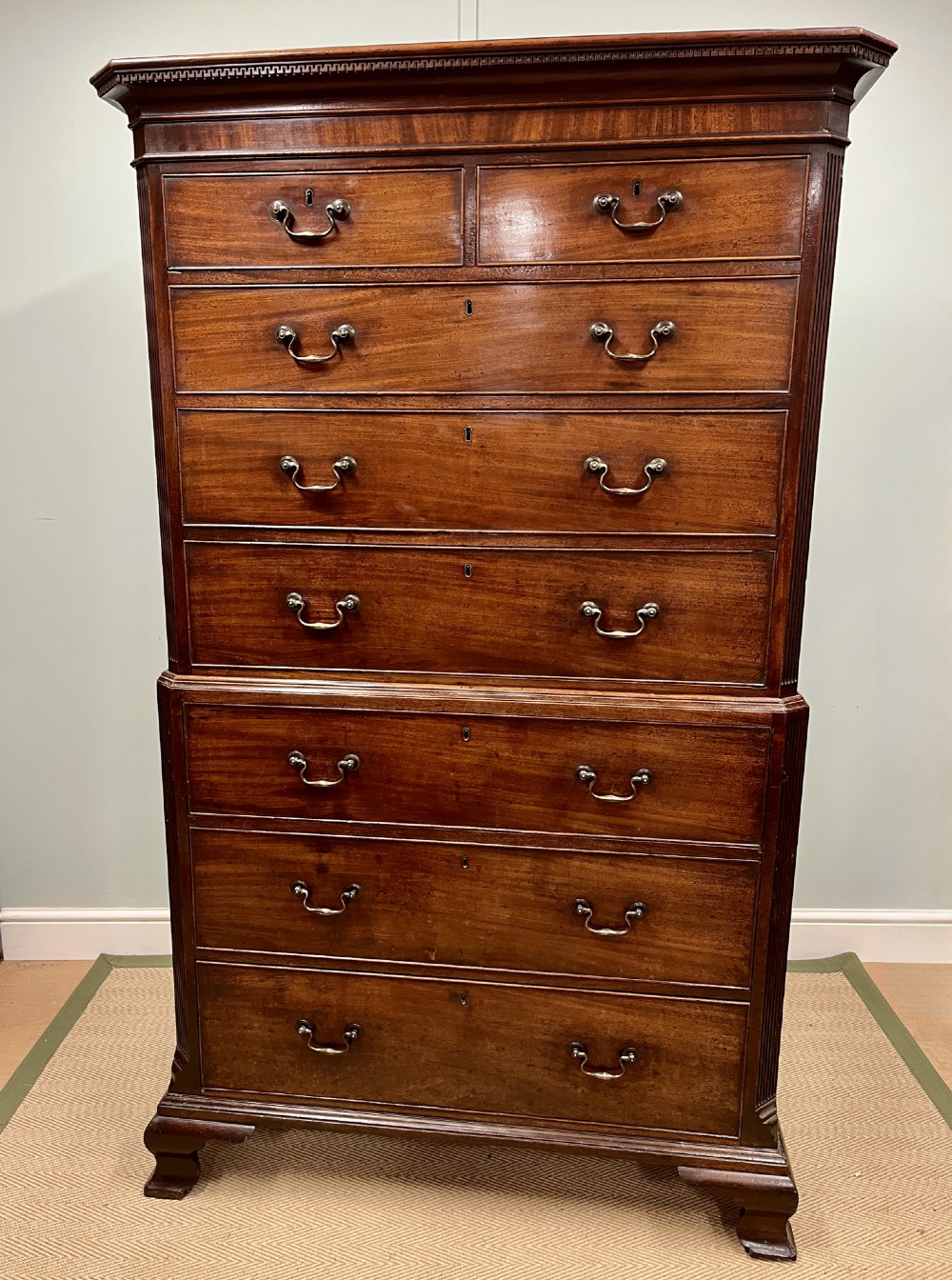 An 18th-century Georgian mahogany chest on chest featuring two short over six long graduated drawers with brass swan-neck handles and ogee bracket feet.