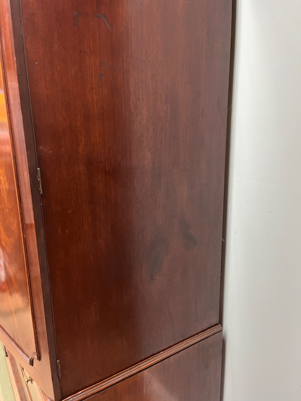 A nineteenth-century flame mahogany linen press featuring panelled cupboard doors above three lower drawers with brass swan-neck handles. View IX