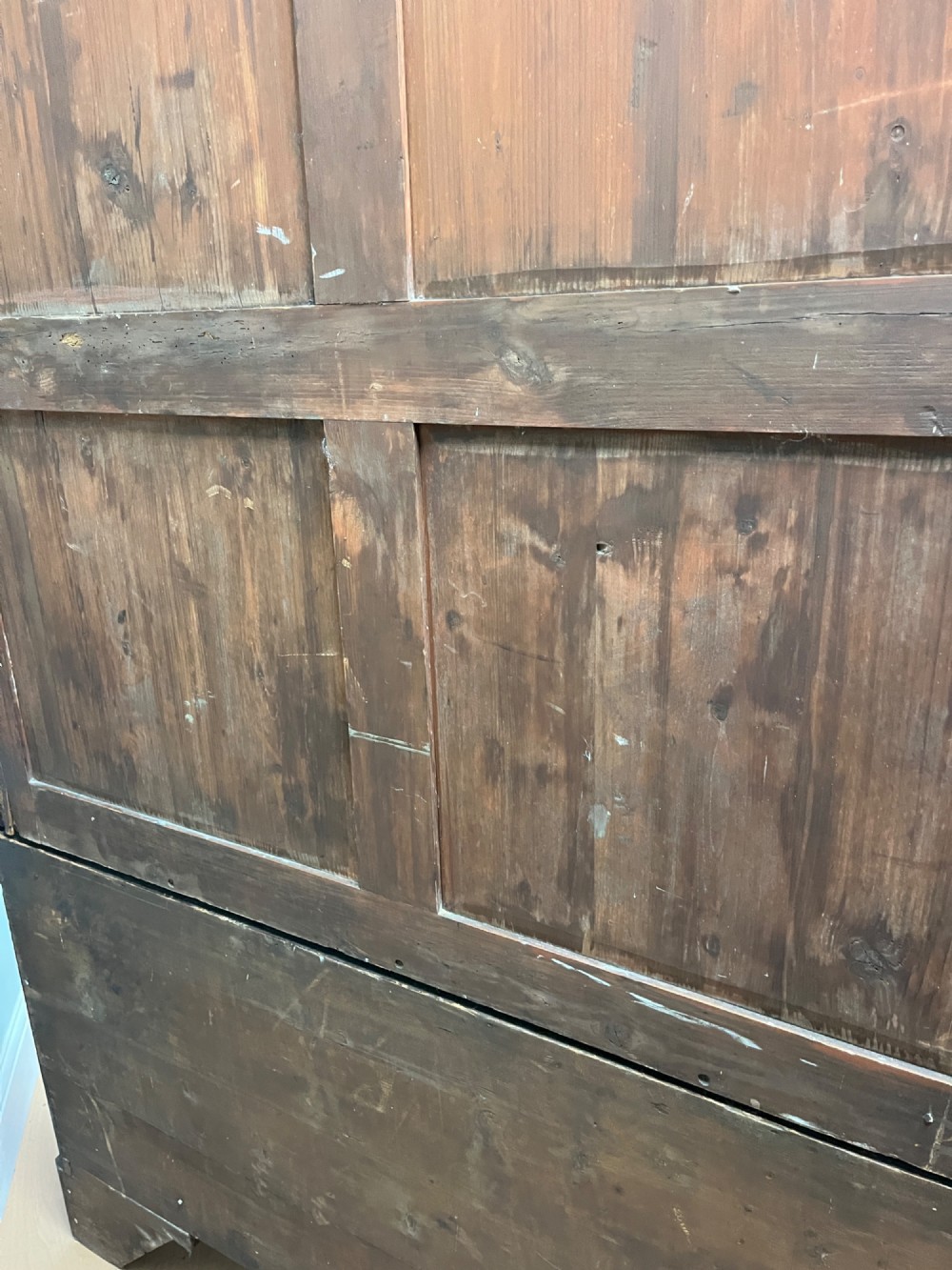A nineteenth-century flame mahogany linen press featuring panelled cupboard doors above three lower drawers with brass swan-neck handles. View X
