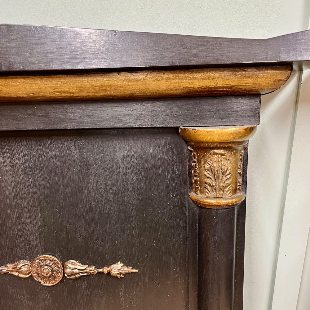 A pair of tall Empire style ebonised pier mirrors featuring gilt column capitals, architectural tops, and classical metal appliques. View V
