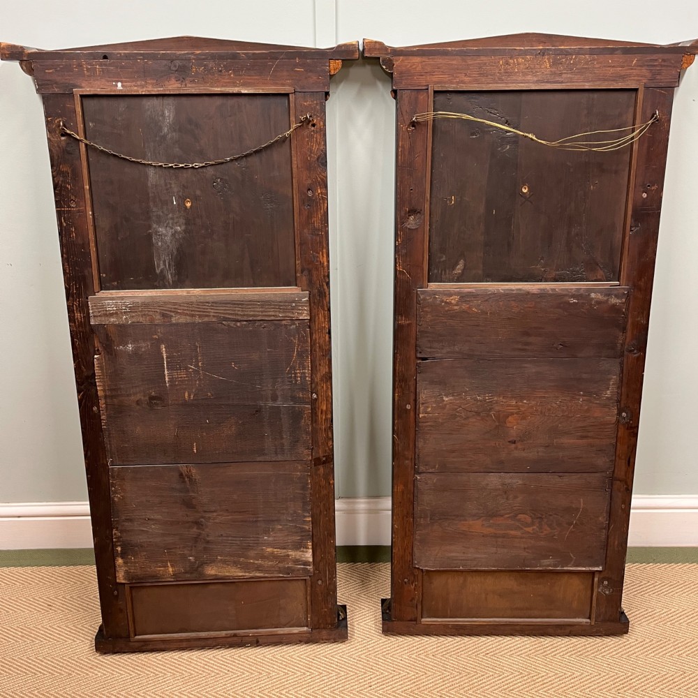 A pair of tall Empire style ebonised pier mirrors featuring gilt column capitals, architectural tops, and classical metal appliques. View VI