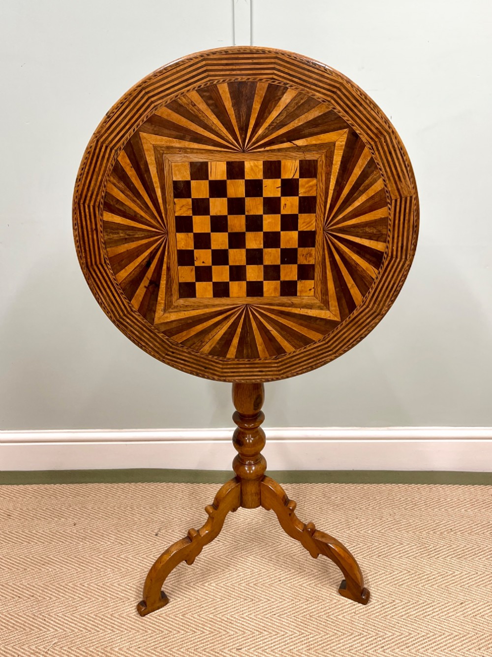 A nineteenth-century Italian circular tilt-top table featuring intricate geometric inlaid wood, a central chessboard design, and a turned pedestal on a tripod base.