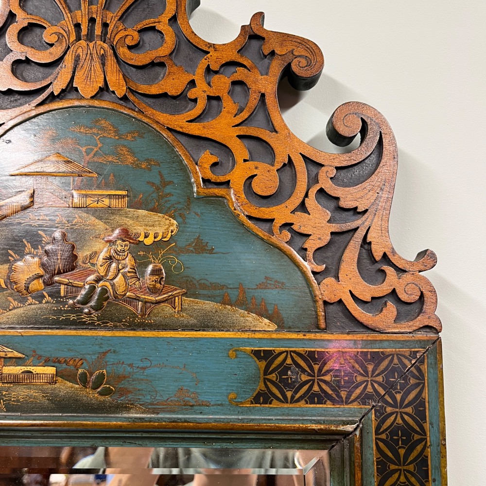 An Edwardian Chinoiserie wall mirror featuring a teal blue and gilt painted wooden frame with hand-painted Asian landscapes and a carved openwork cresting. View V