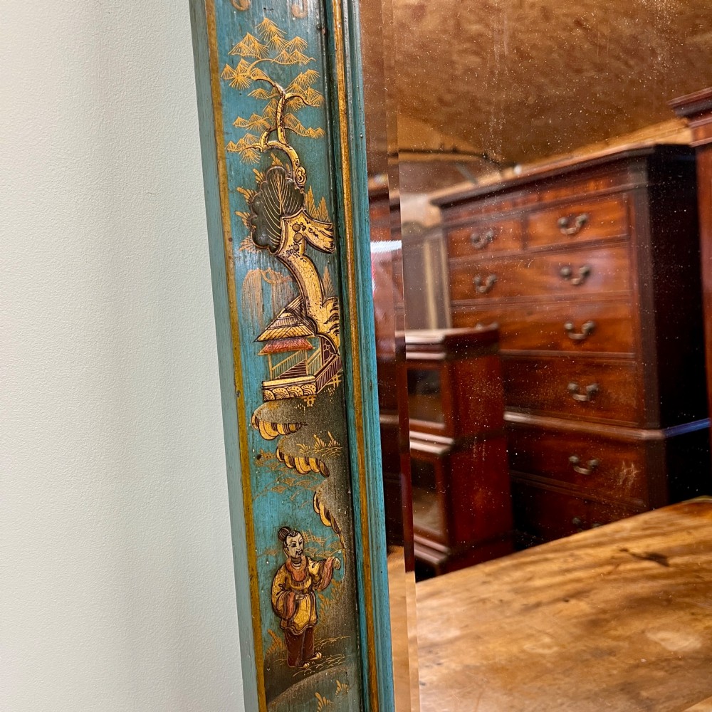 An Edwardian Chinoiserie wall mirror featuring a teal blue and gilt painted wooden frame with hand-painted Asian landscapes and a carved openwork cresting. View VI