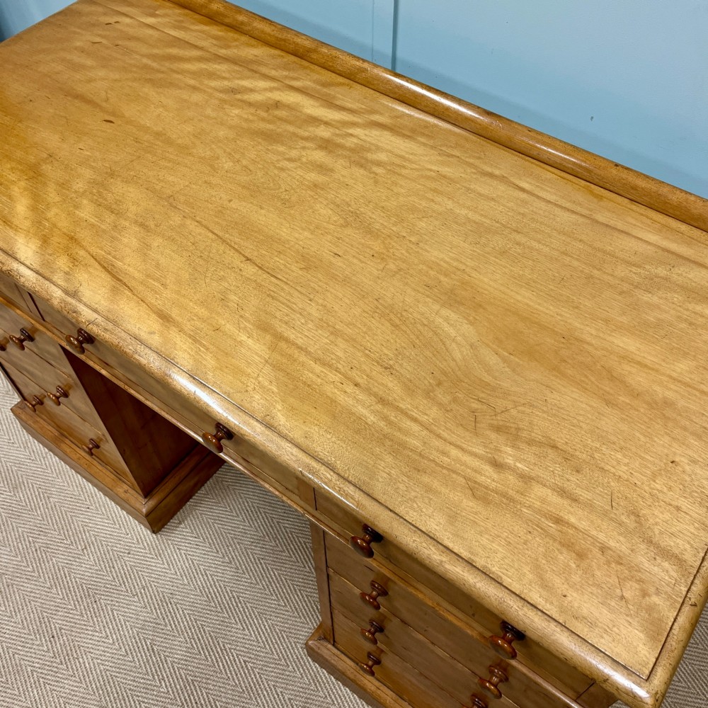 A 19th-century satin birch twin-pedestal desk featuring nine drawers with turned wooden knobs and a low gallery back. View VII