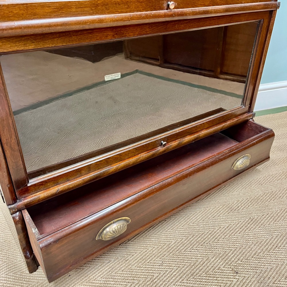An Edwardian Globe Wernicke four-section dark mahogany barrister bookcase featuring glazed lifting doors, brass handles, and a base drawer. View V