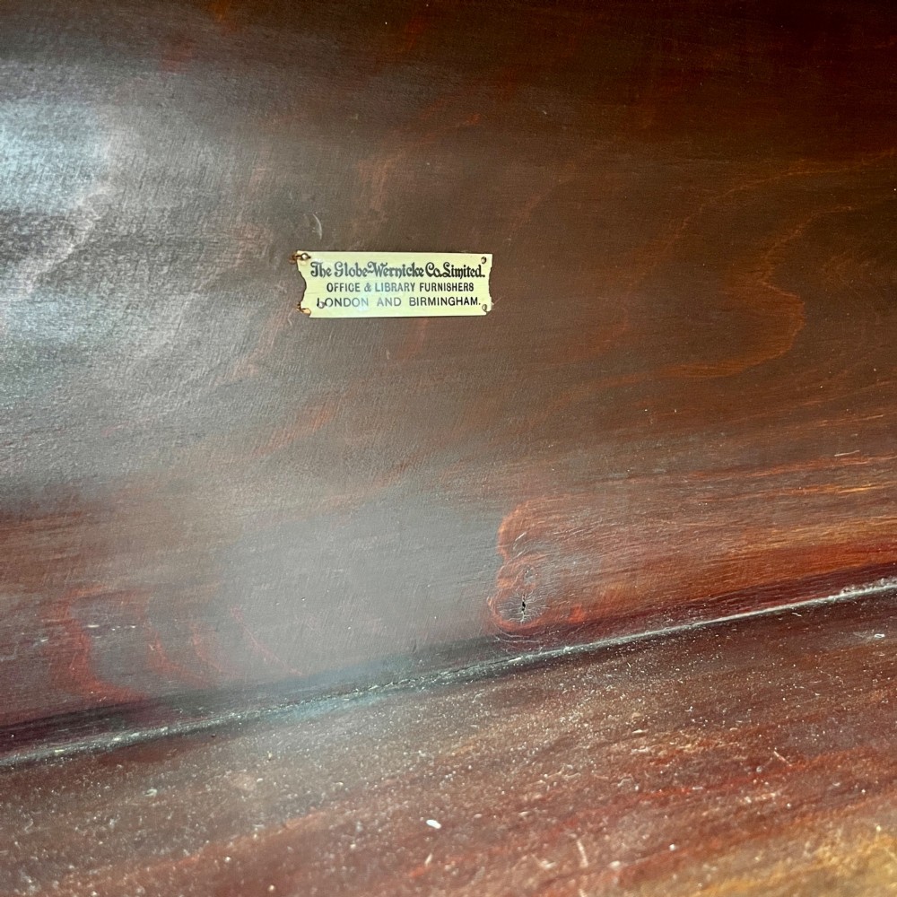 An Edwardian Globe Wernicke four-section dark mahogany barrister bookcase featuring glazed lifting doors, brass handles, and a base drawer. View VII
