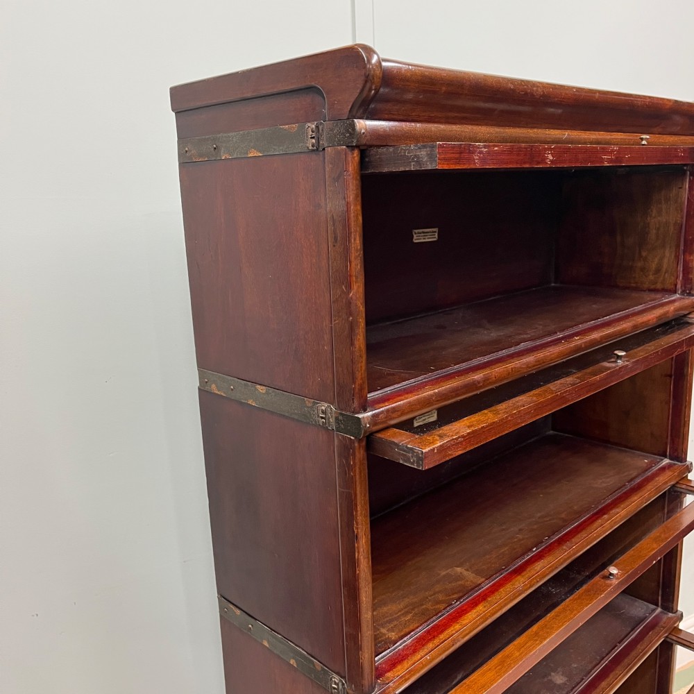 An Edwardian Globe Wernicke four-section dark mahogany barrister bookcase featuring glazed lifting doors, brass handles, and a base drawer. View VIII