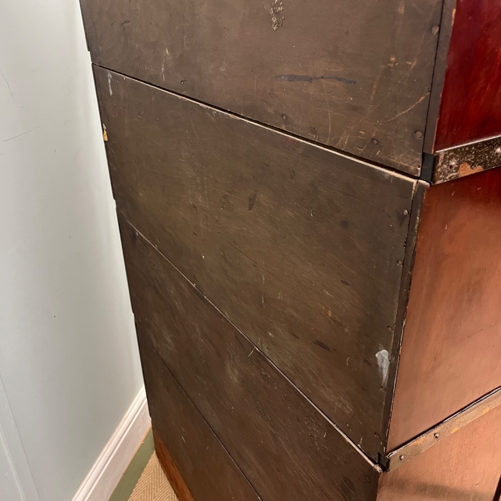 An Edwardian Globe Wernicke four-section dark mahogany barrister bookcase featuring glazed lifting doors, brass handles, and a base drawer. View X