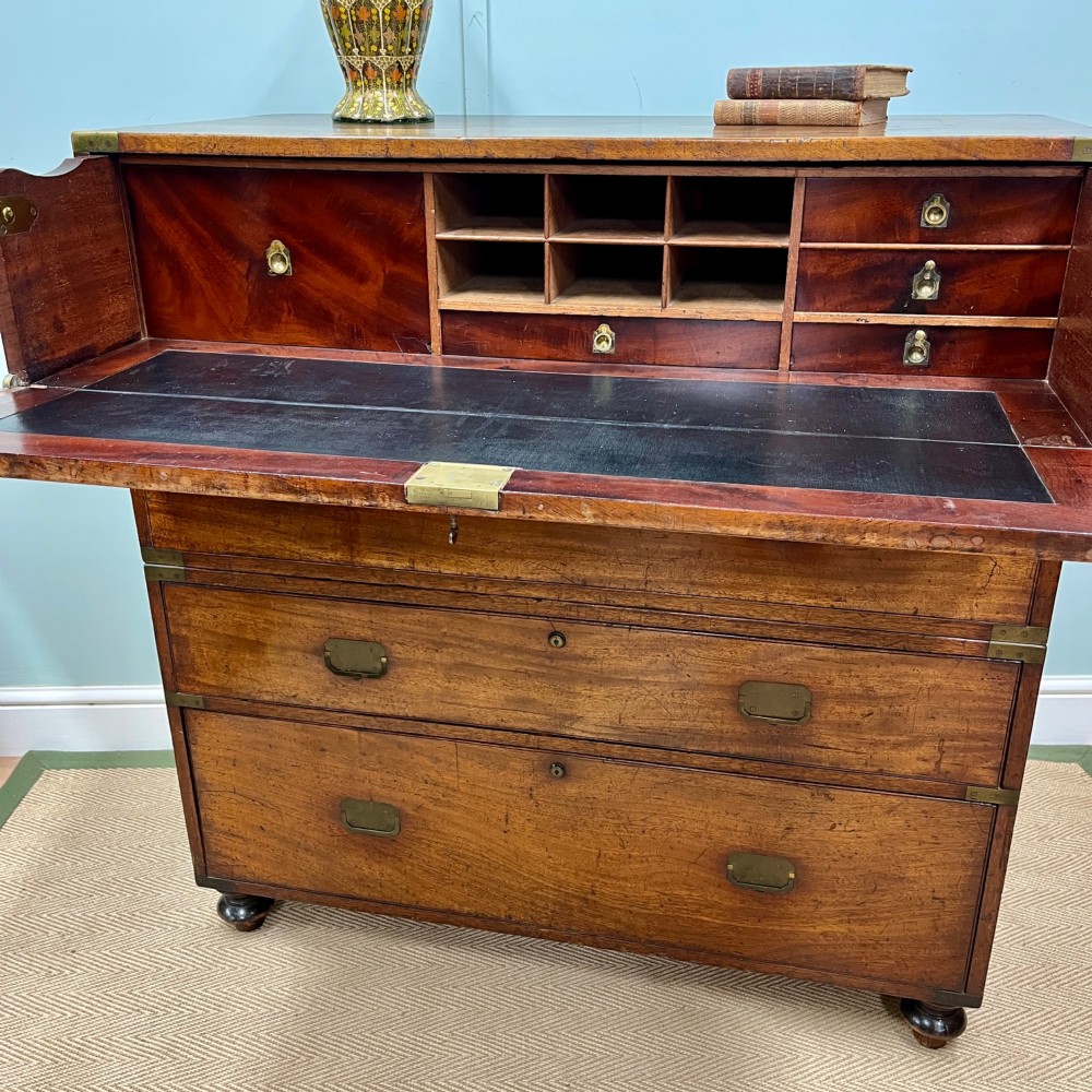 A 19th-century mahogany military campaign secretaire chest featuring four drawers with recessed brass handles and brass corner straps, resting on turned feet. View II
