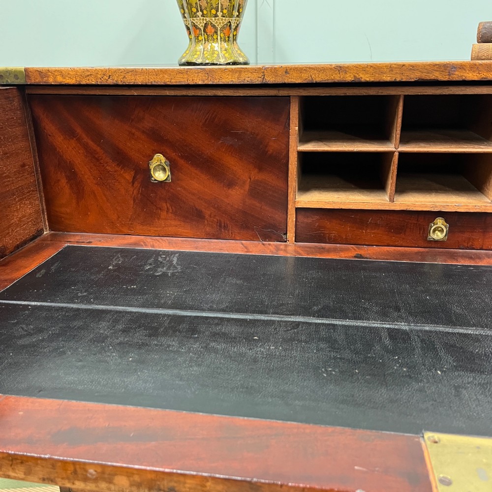A 19th-century mahogany military campaign secretaire chest featuring four drawers with recessed brass handles and brass corner straps, resting on turned feet. View III