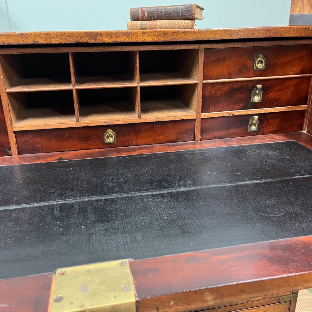 A 19th-century mahogany military campaign secretaire chest featuring four drawers with recessed brass handles and brass corner straps, resting on turned feet. View IV