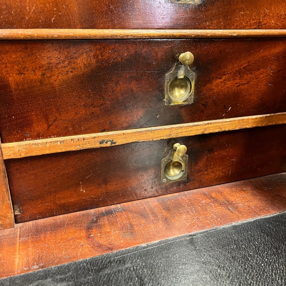 A 19th-century mahogany military campaign secretaire chest featuring four drawers with recessed brass handles and brass corner straps, resting on turned feet. View V